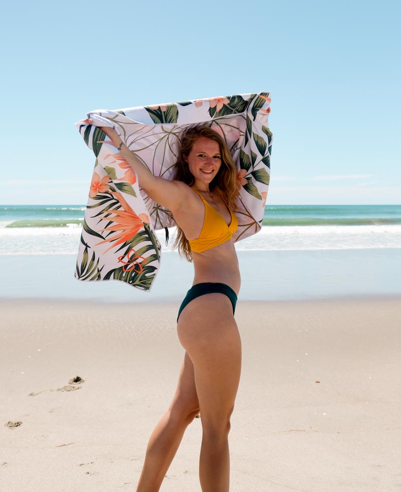 MAHĀNA Birds of Paradise beach towel lifestyle shot – quick-dry recycled towel at the beach on a sunny day