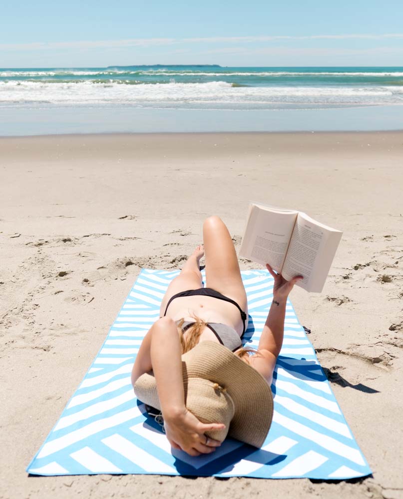 MAHĀNA Santorini beach towel lifestyle shot – sand-free towel on the beach